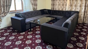 Ein Wohnzimmer mit einem Ecksofa, einem Glastisch und einem Teppich mit Muster.