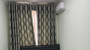 Ein Schlafzimmer mit einem Bett, gemusterten Vorhängen und einer Klimaanlage.