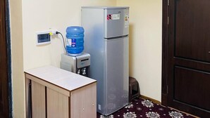 Ein gemütlicher Raum mit Küchenzeile, Wasserspender und Kühlschrank.