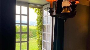 Una habitación con un ventanal grande, una lámpara colgante y una silla.