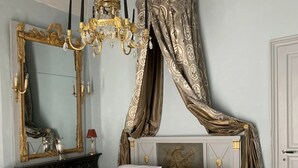 Un dormitorio con cama, candelabro, espejo y dosel.