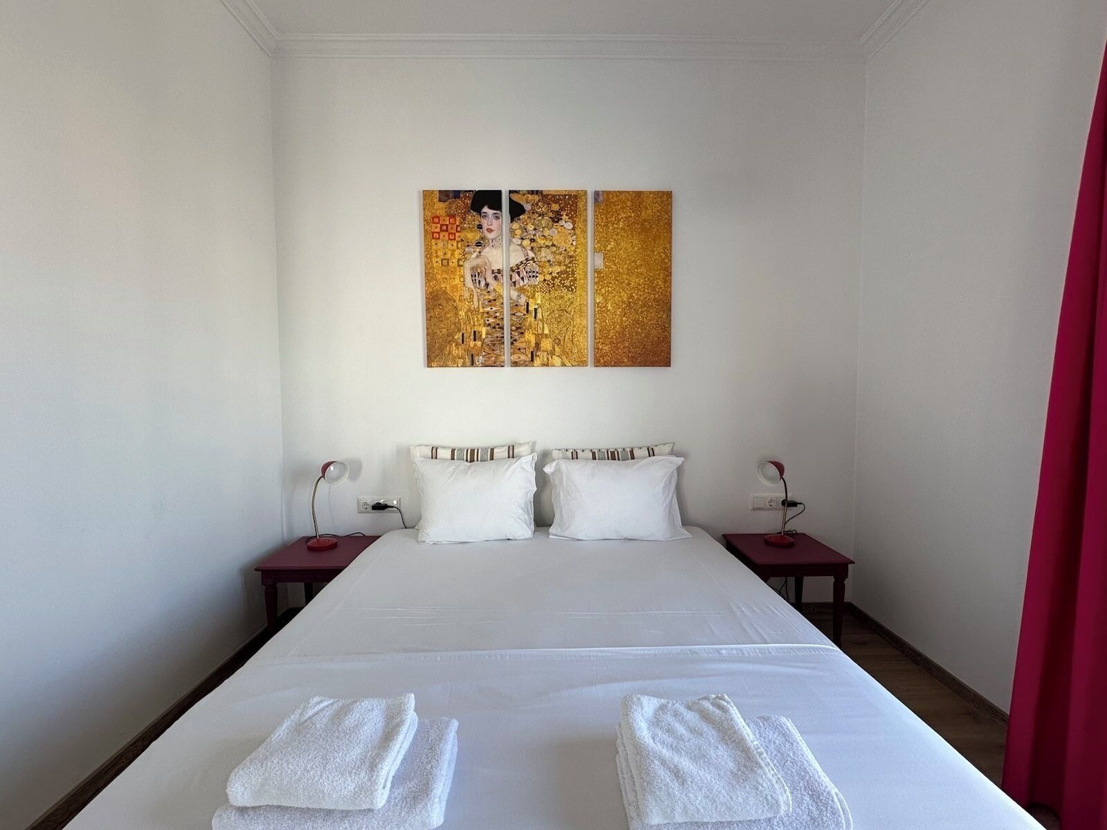 Quarto de hotel com uma cama grande, duas mesas de cabeceira e um quadro acima da cama.