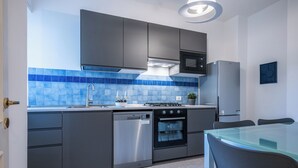 A modern kitchen with grey cabinets, a stainless steel dishwasher, a built-in oven, a microwave, and a refrigerator. - Velvet Stay | Ravizza 41 by Pleiades Home (Livorno)