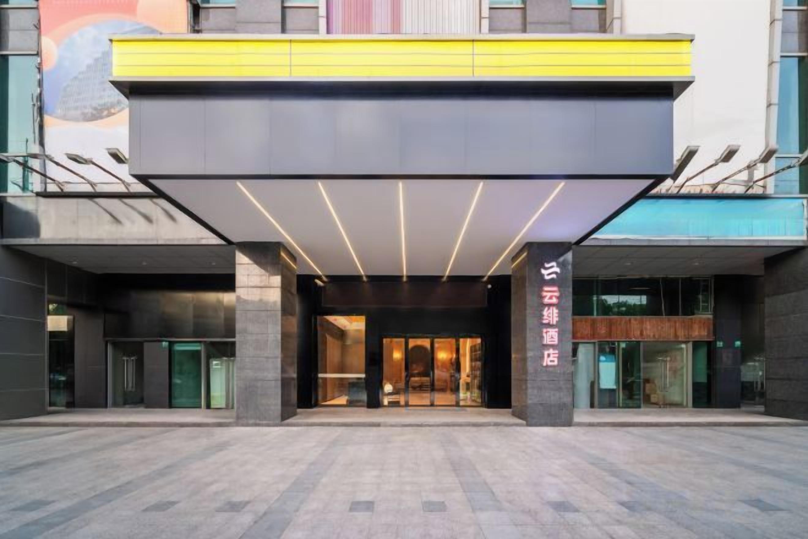 A hotel entrance with a modern design, featuring a large overhang and a glass facade.