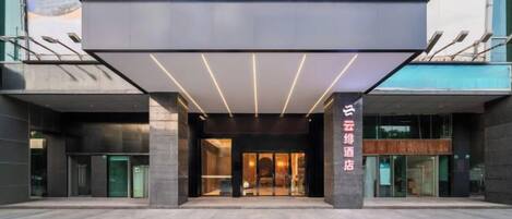 A hotel entrance with a modern design, featuring a large overhang and a glass facade.