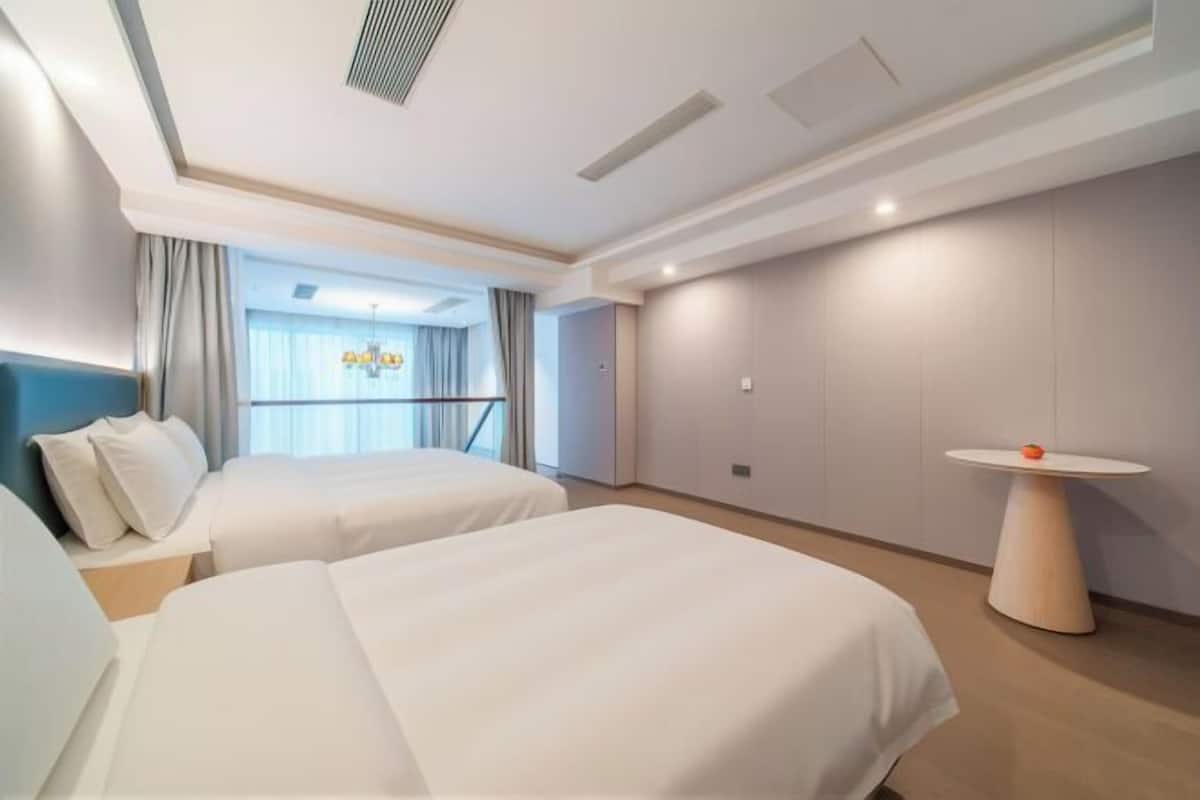 A hotel room with two beds, a small table, and a view of the outdoors.
