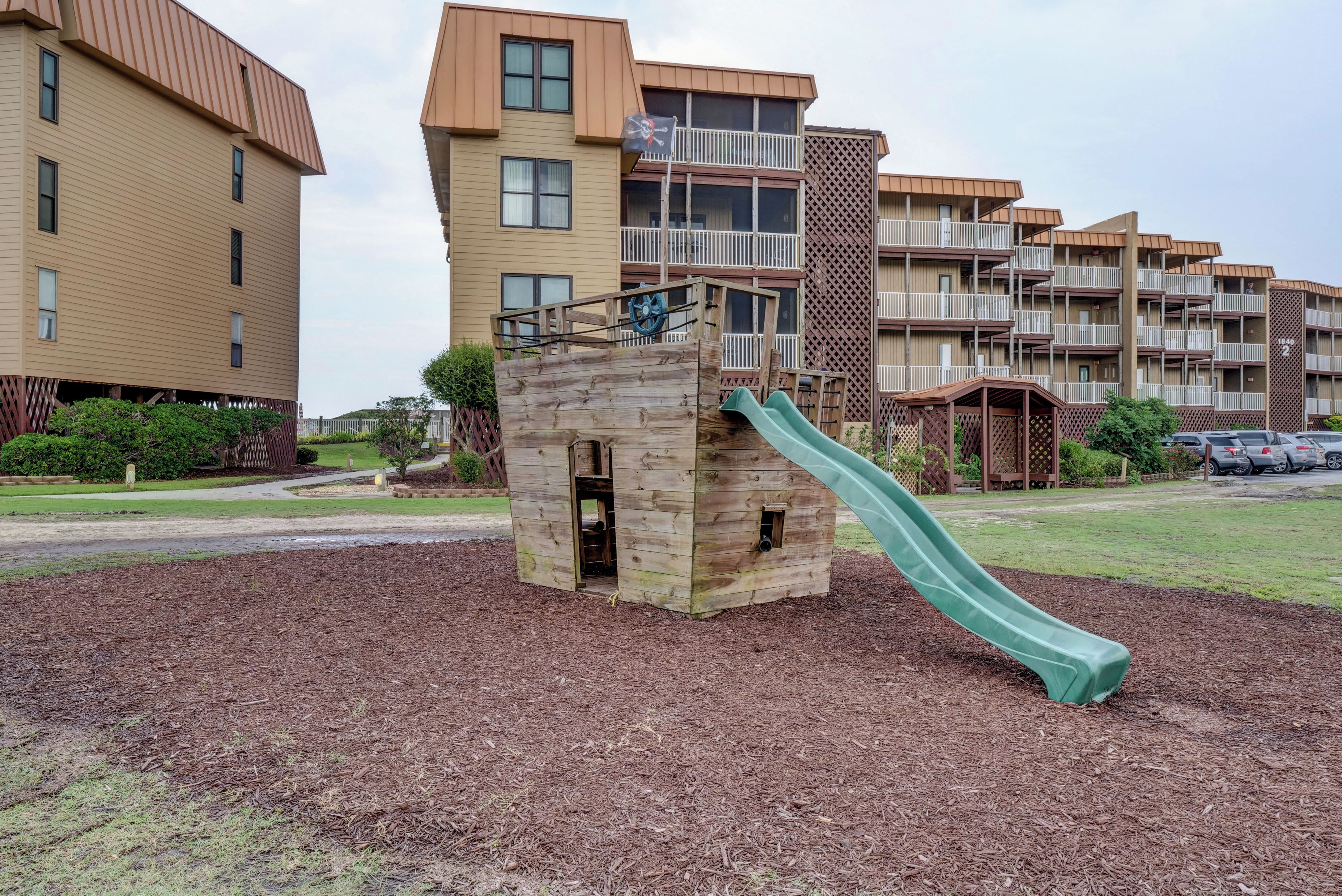 A playground with a slide, surrounded by a playground area with mulch.