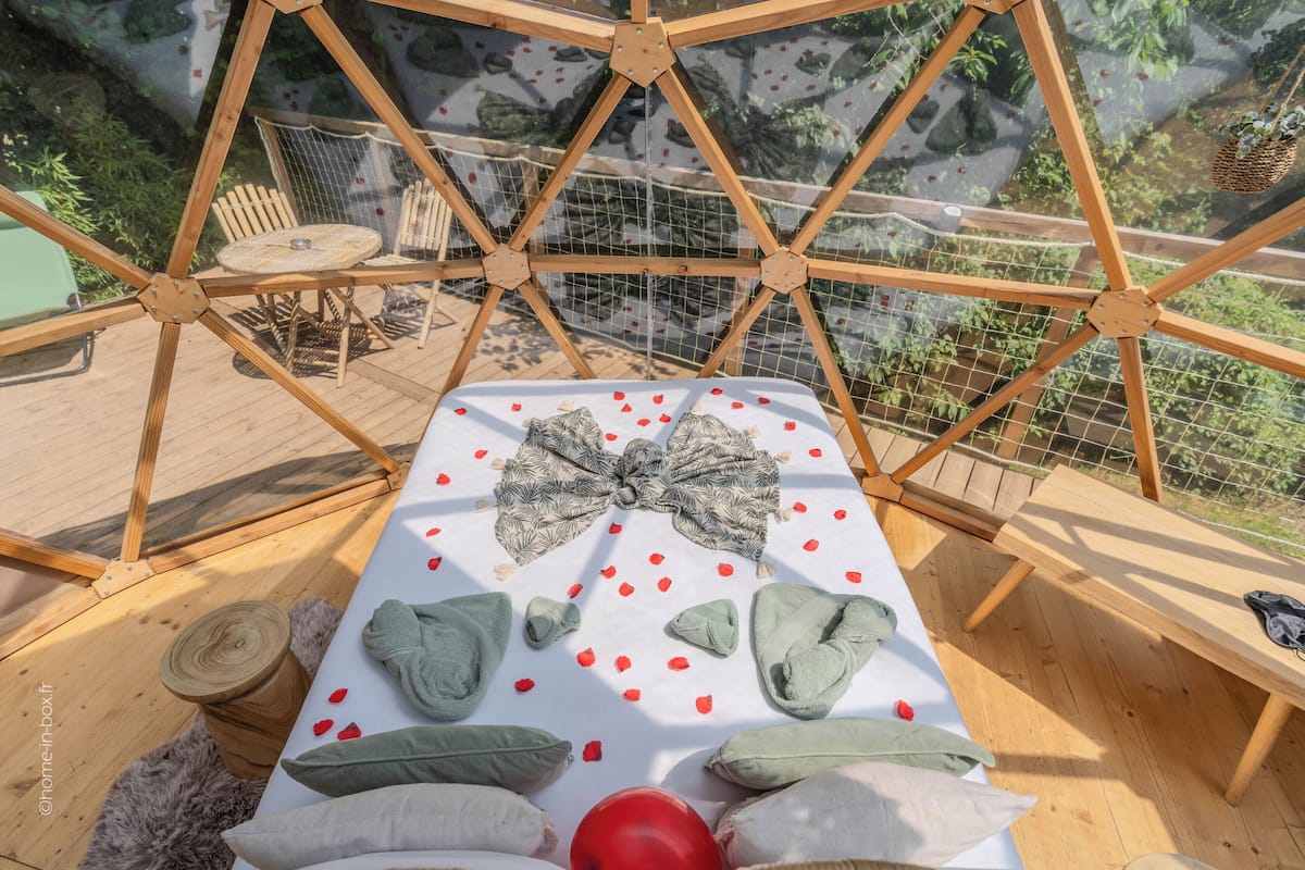 A wooden bed with a white sheet, green pillows, and a red balloon.