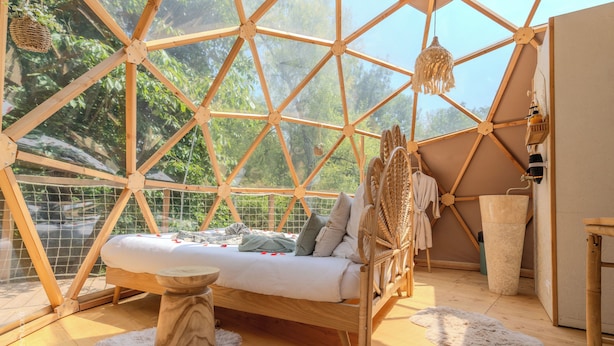 Una habitación acogedora con un diseño geométrico, una cama, muebles de madera y vistas a zonas verdes.