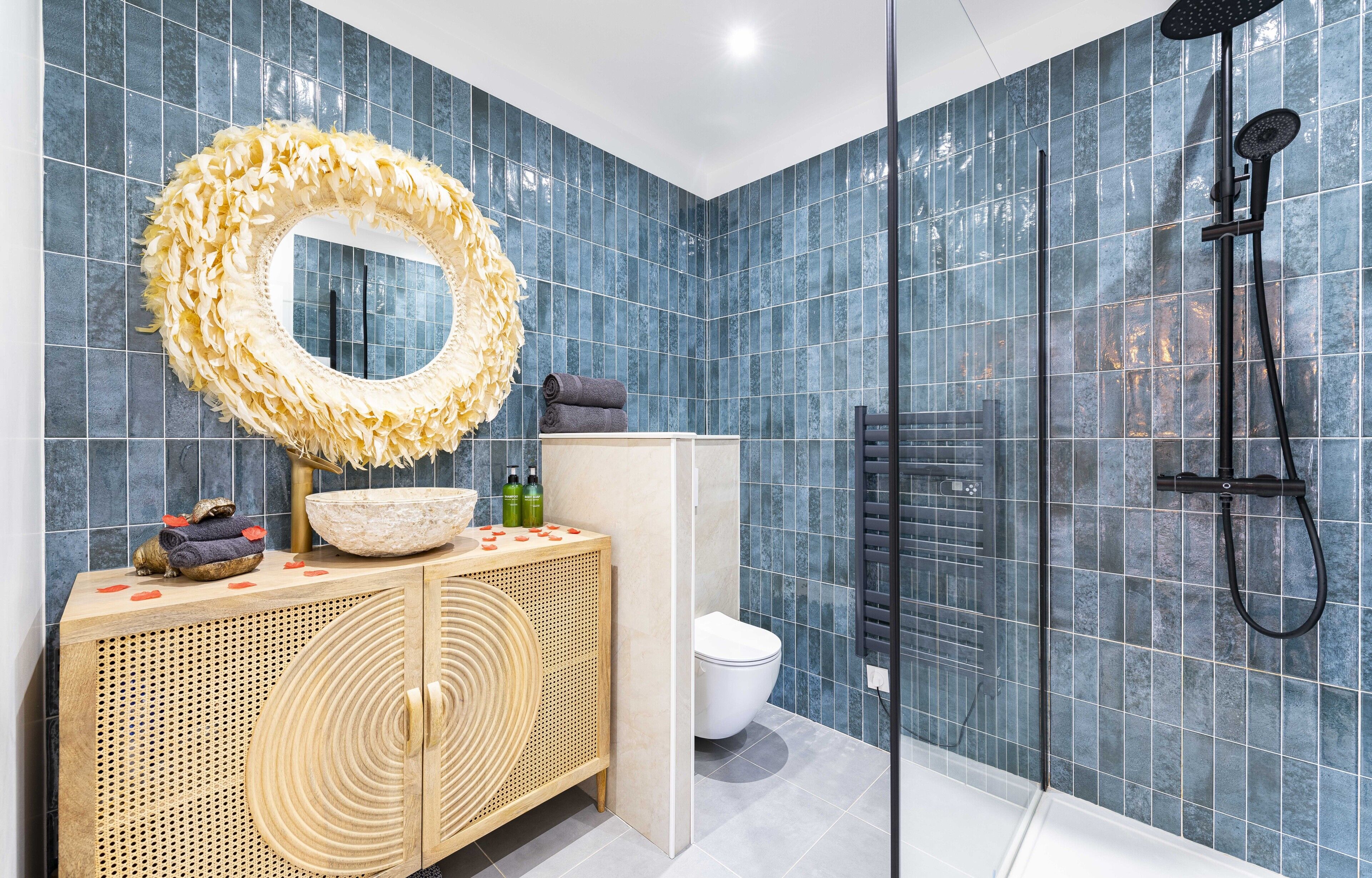 Un baño con un espejo grande, ducha y tocador con artículos de aseo.