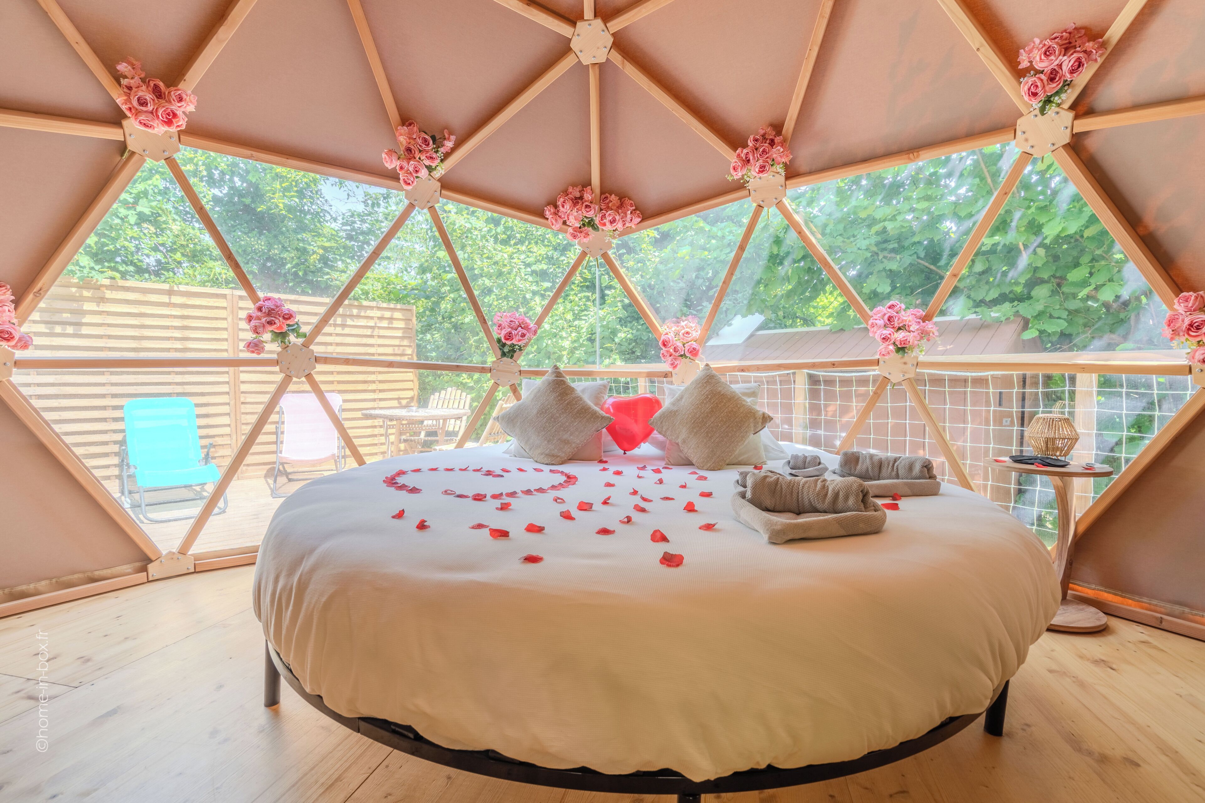 A bedroom with a bed, pillows, and a view through a geometric window.