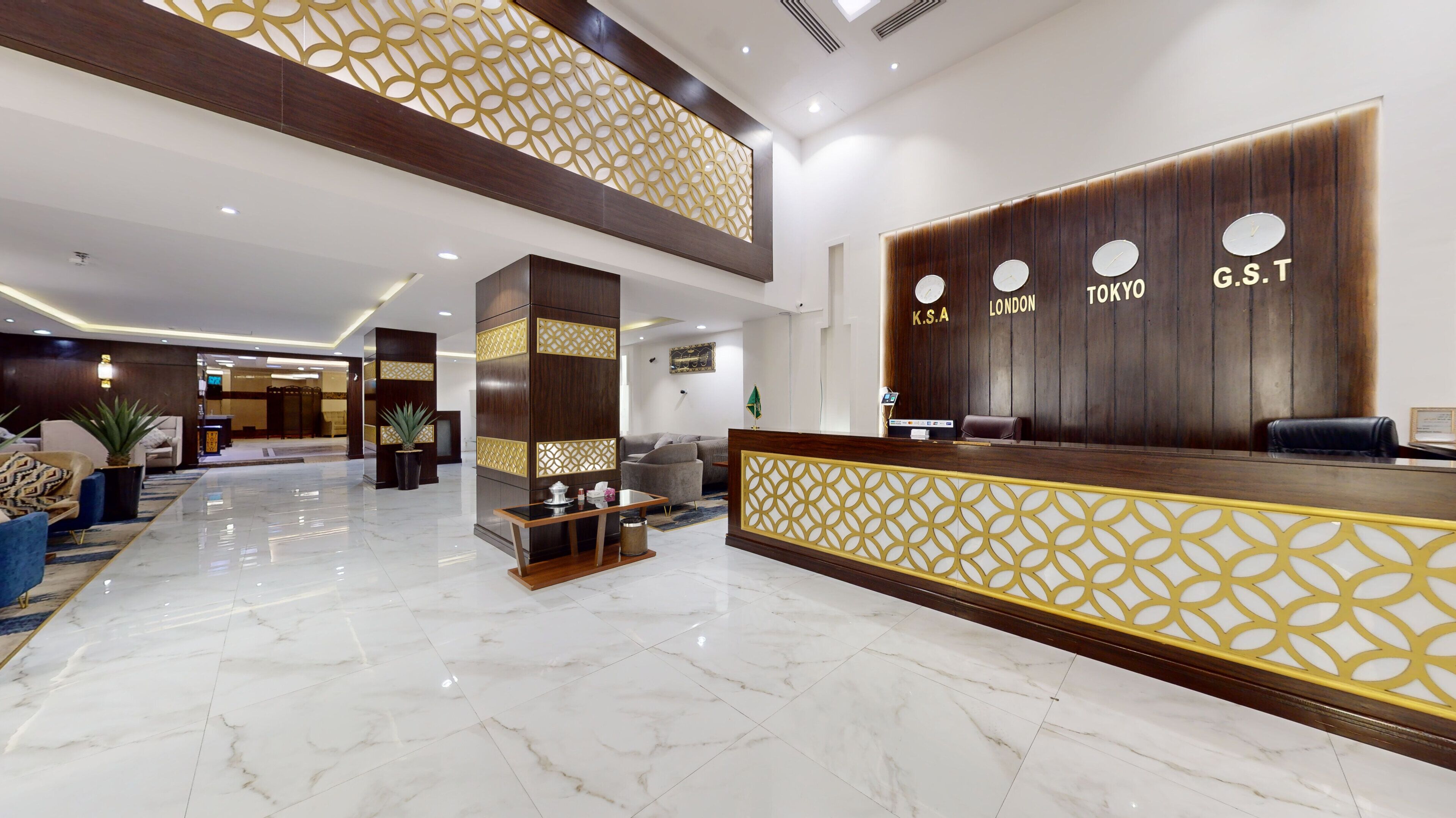 Un vestíbulo de hotel con mostrador de recepción, zona de estar y un techo alto con paneles decorativos.