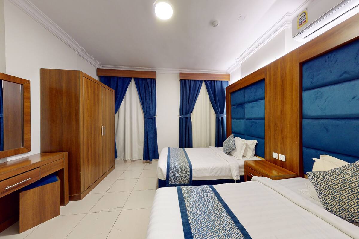 A hotel room with a bed, bedside tables, a wardrobe, and a mirror.
