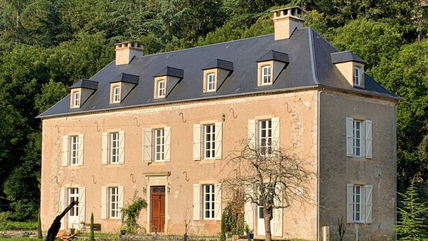 A large, two-story stone building with a steeply pitched roof and multiple windows with shutters. - Noubar  (Cénevières)