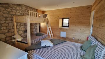 Un dormitorio con literas, una pared de madera, una pared de piedra, una ventana y una mesita de noche.