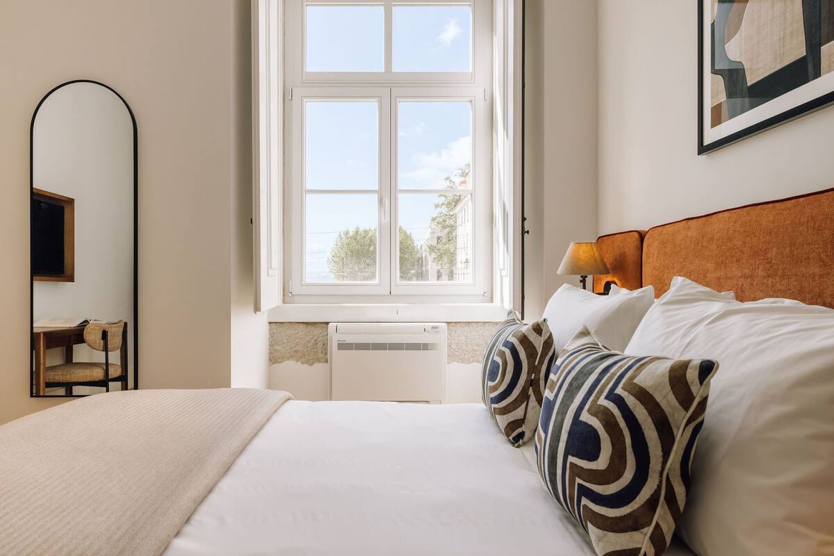 Ein Hotelzimmer mit einem großen Bett, einem Fenster mit Blick, einem Schreibtisch mit Stuhl und einem Spiegel.