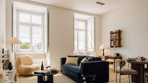 A modern living room with a sofa, armchair, coffee table, and dining table. - Ando Living Corpo Santo House (Lisbon)