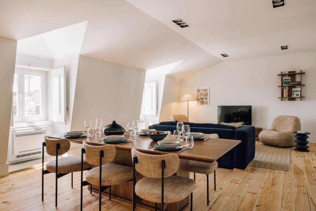 Ein modernes Wohnzimmer mit Essbereich, mit Holzboden, einer Couch, einem Fernseher und einem Bücherregal.