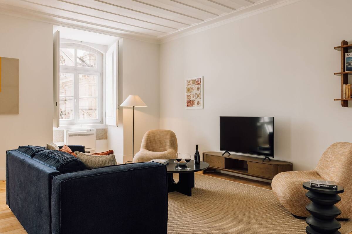 Ein modernes Wohnzimmer mit einer Couch, einem Couchtisch, einem Fernseher und einer Lampe.
