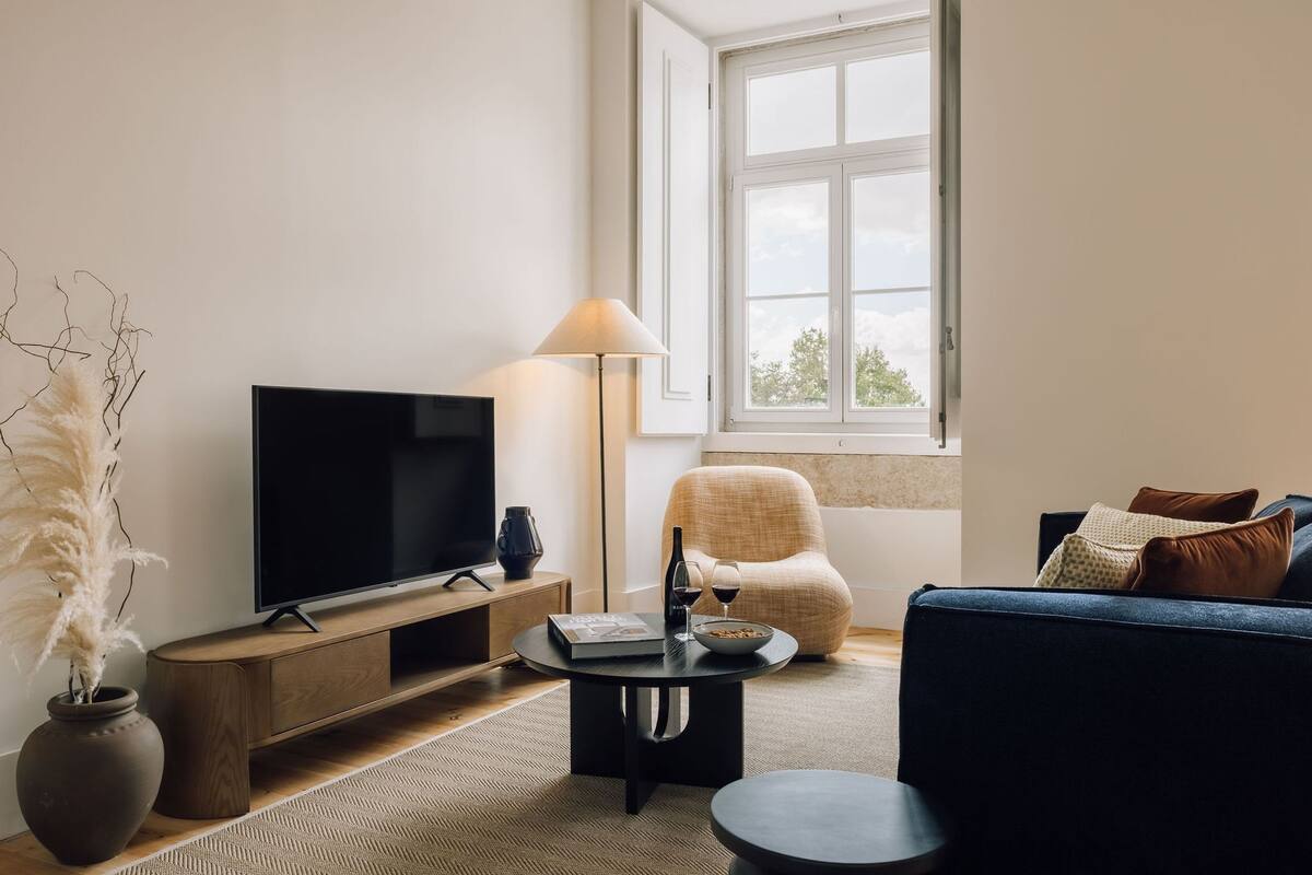 Ein modernes Wohnzimmer mit Flachbildfernseher, rundem Couchtisch, Sofa und Sessel.