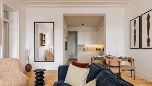 A modern living room with a blue sofa, a round coffee table, and a dining area with a wooden table and chairs. - Ando Living Corpo Santo House (Lisbon)