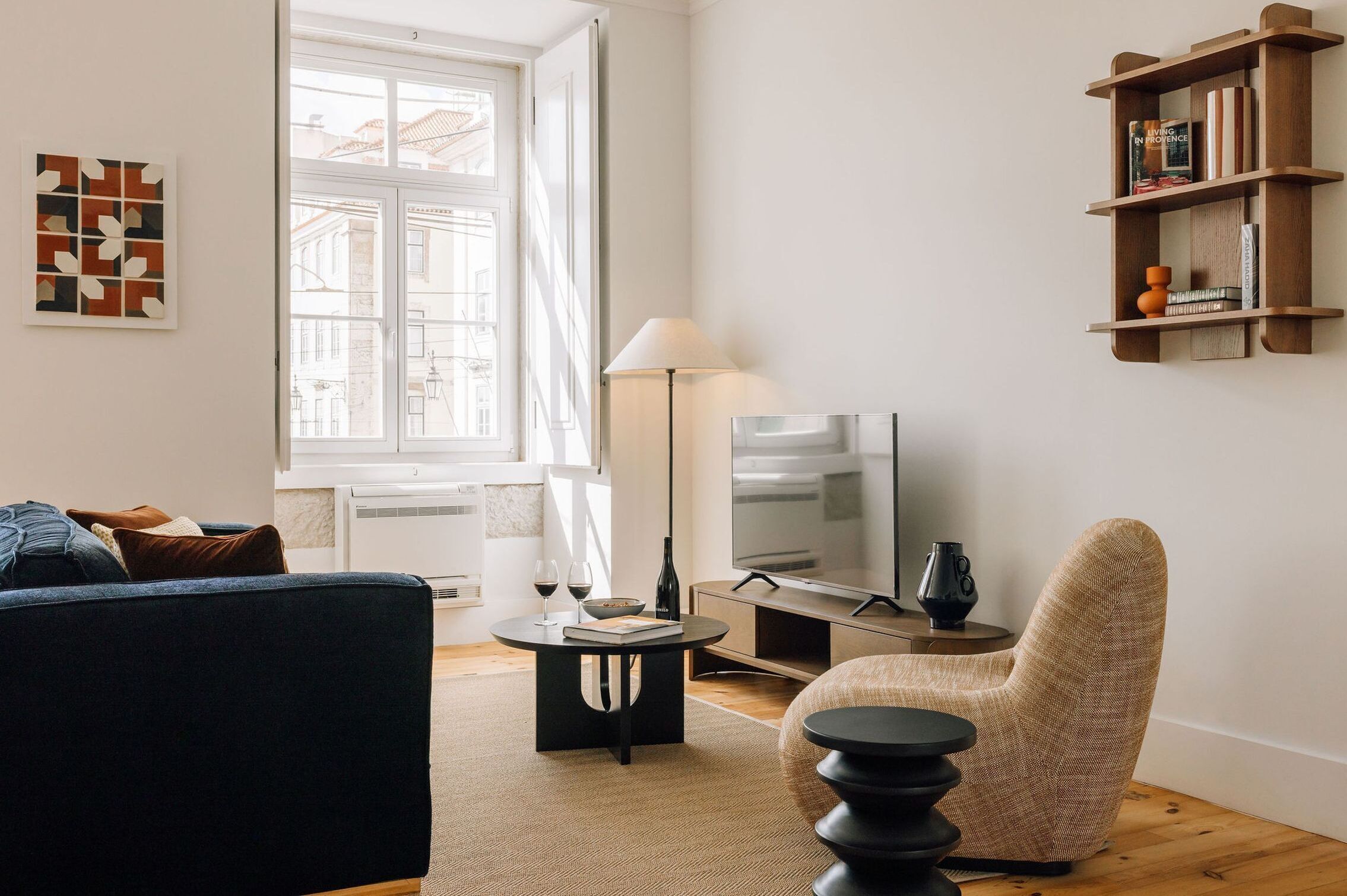 A modern living room with a sofa, a round coffee table, a TV, a lamp, and a bookshelf.