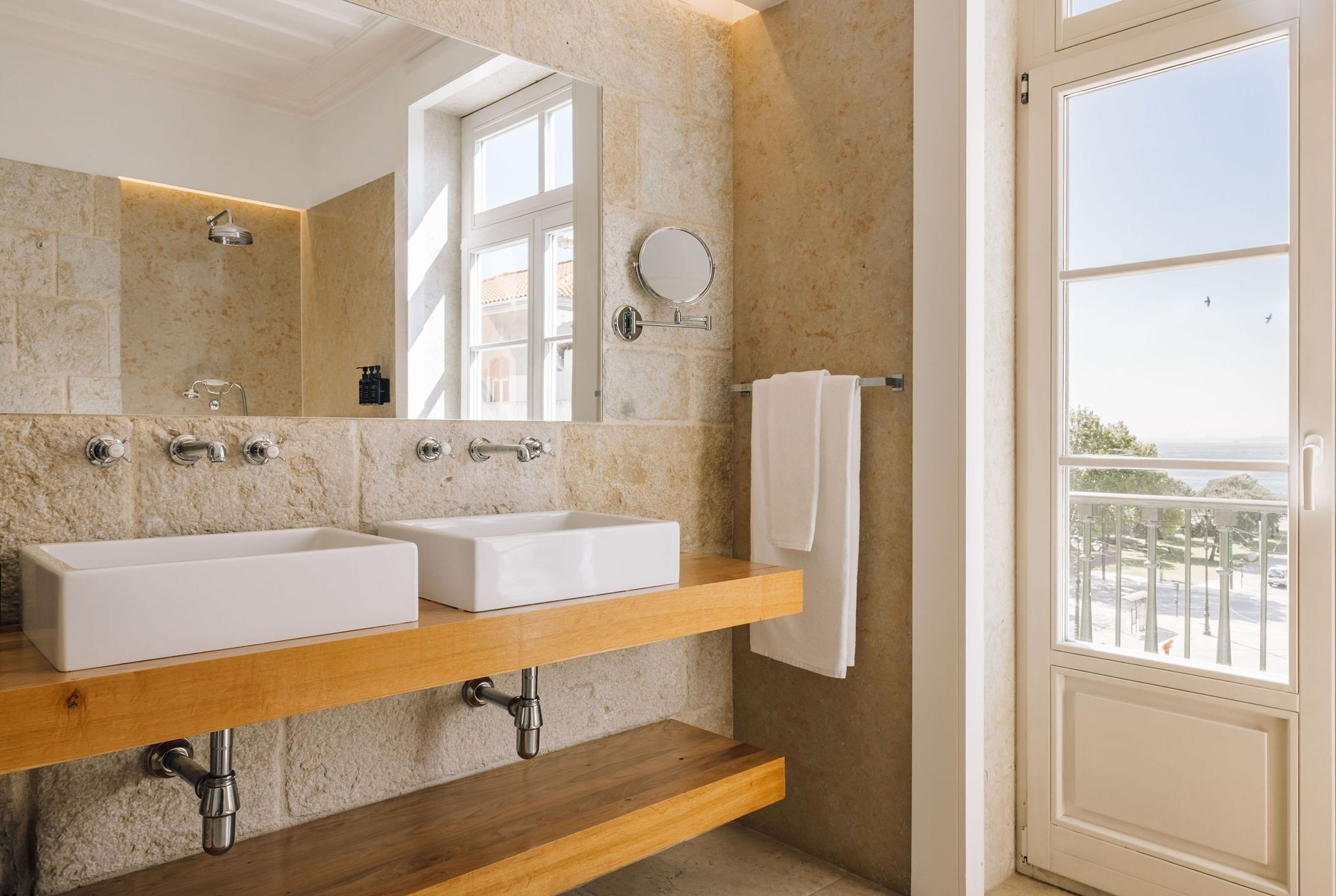 Un baño con dos lavamanos, un espejo y una ventana con vistas.