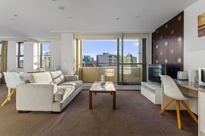 Relax in this spacious living room with a sofa, dining area, and kitchen, offering a city view.