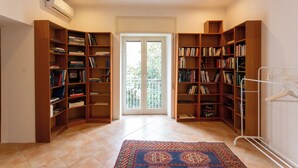A spacious room with a large bookshelf filled with books, a patterned rug, and a door leading to a balcony. - Vico Santa Maria del Pozzo 9 (Naples)