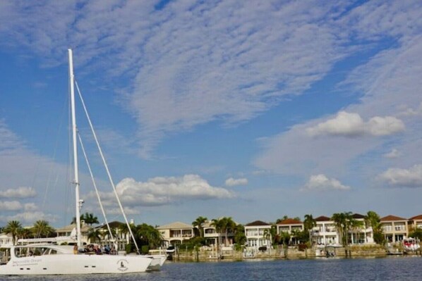 A waterfront property with a large sailboat docked, a marina, and a row of houses with balconies. - Indian Rocks Beach Gem - Renovated 2BR Beach House (Indian Rocks Beach)