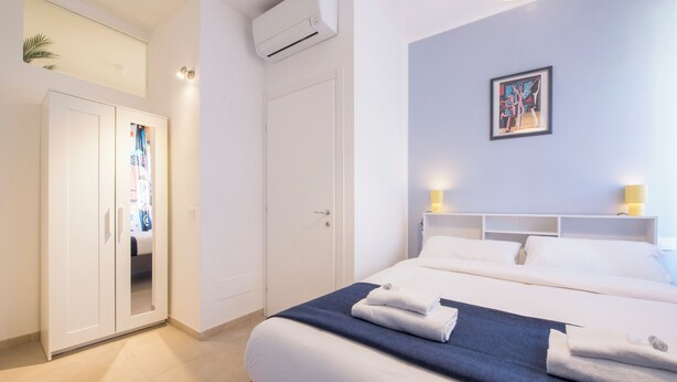 Una habitación de hotel moderna con una cama grande, un armario y un cuadro en la pared.