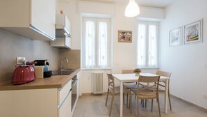 Una cocina moderna con un hervidor rojo, una mesa blanca y dos sillas.