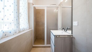 Un baño con ducha, lavabo y espejo.