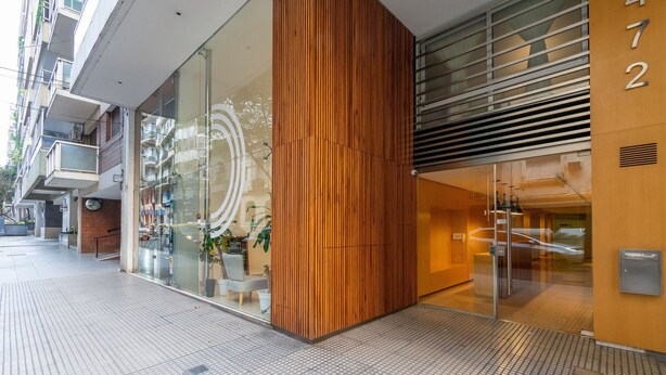 A modern building facade with a glass entrance, a wooden panel accent, and a visible number '472'. - Ayacucho Apartment | Style & Comfort in Recoleta (Ciudad Autónoma de Buenos Aires)