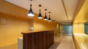A modern reception area with a wooden reception desk, black pendant lights, and a tiled floor. - Ayacucho Apartment | Style & Comfort in Recoleta (Ciudad Autónoma de Buenos Aires)