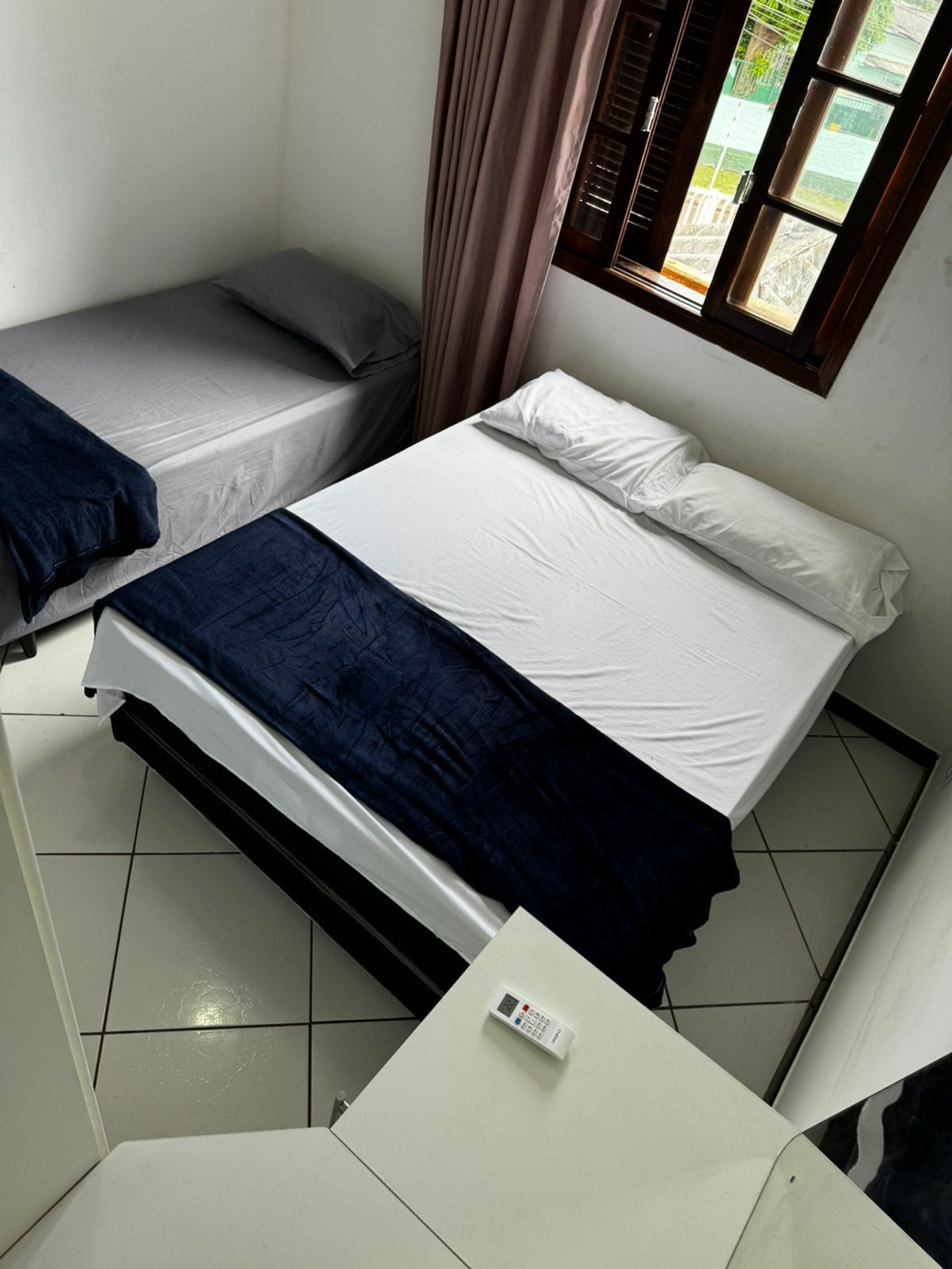 Habitació petita i neta, amb llit, escriptori i finestra amb cortines.