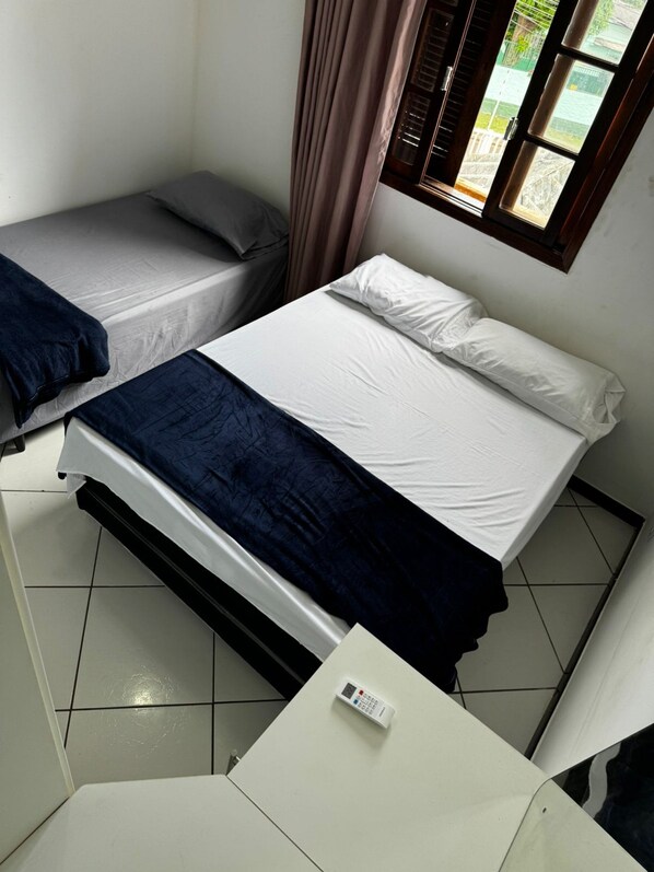 Una habitación pequeña y limpia con una cama, un escritorio y una ventana con cortinas.