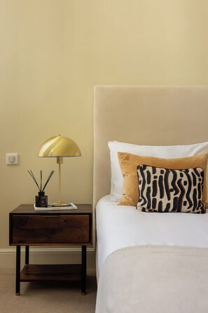 A bedroom with a bed, a nightstand, a lamp, and a book.