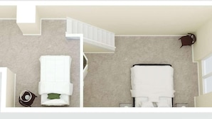 Una habitación de hotel con cama, sofá, una mesita con lámpara y una escalera.