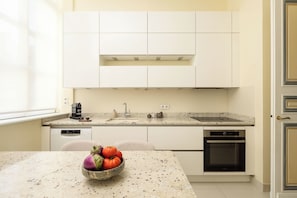 Une cuisine moderne avec des meubles blancs, un plan de travail en granit et un four encastré.