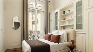 Un dormitorio con cama, mesita de noche y ventana con vistas a un balcón.
