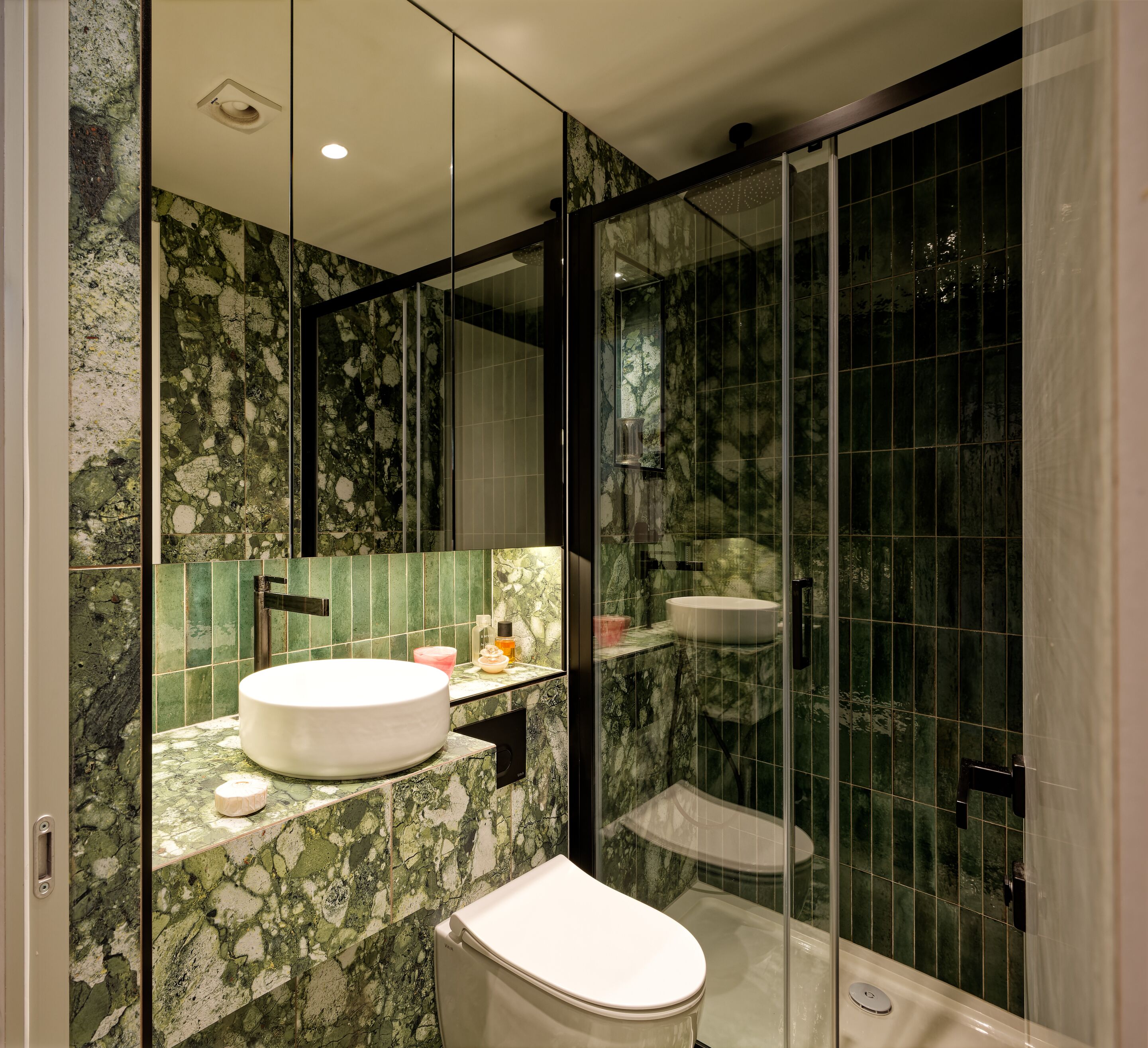 Ein modernes Badezimmer mit Marmorwaschtisch, Toilette und einer Duschkabine.