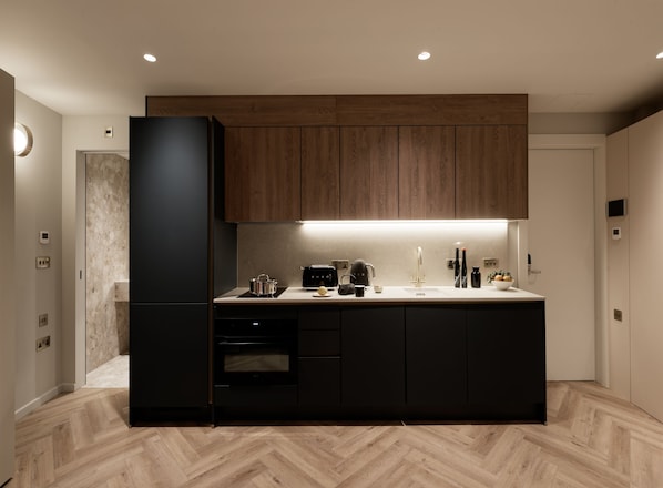 A modern kitchen with dark cabinetry, a built-in oven, and a countertop with various appliances.