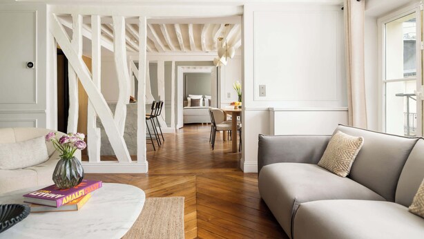Ein modernes Wohnzimmer mit einer Couch, einem Couchtisch und einem Essbereich im Hintergrund.