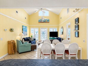 A dining area with a table and chairs, a sofa, and a television.