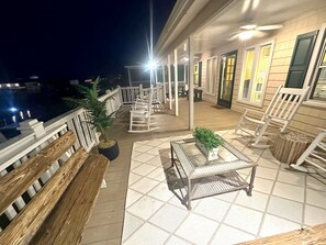 Una terraza al aire libre techada con asientos, una mesa y plantas en macetas.