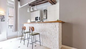 Eine moderne Küche mit einer weißen Kücheninsel, zwei Barhocker und Pendelleuchten.