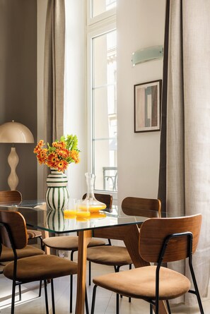 Un comedor moderno con una mesa de vidrio, un florero a rayas y sillas de madera.