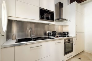 Una cocina moderna con electrodomésticos de acero inoxidable, un lavamanos doble y un horno empotrado.