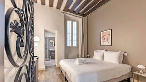 Ein modernes Hotelzimmer mit einem großen Bett, einem begehbaren Kleiderschrank und einem Badezimmer mit Dusche und Toilette.